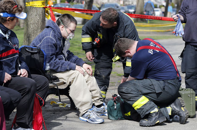 Firefighters tend to a man following an explosion at the finish line of the Boston Marathon in Boston, Monday, April 15, 2013. Two bombs exploded at the Boston Marathon finish line Monday killing at least two people injuring dozens. (AP Photo/Michael Dwyer)
