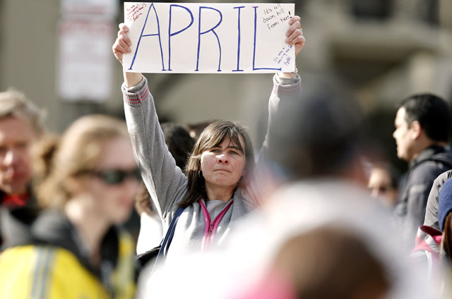 Justine Franco of Montpelier, Vt., holds up a sign near Copley Square in Boston looking for her missing friend, April, who was running in her first Boston Marathon Monday, April 15, 2013.