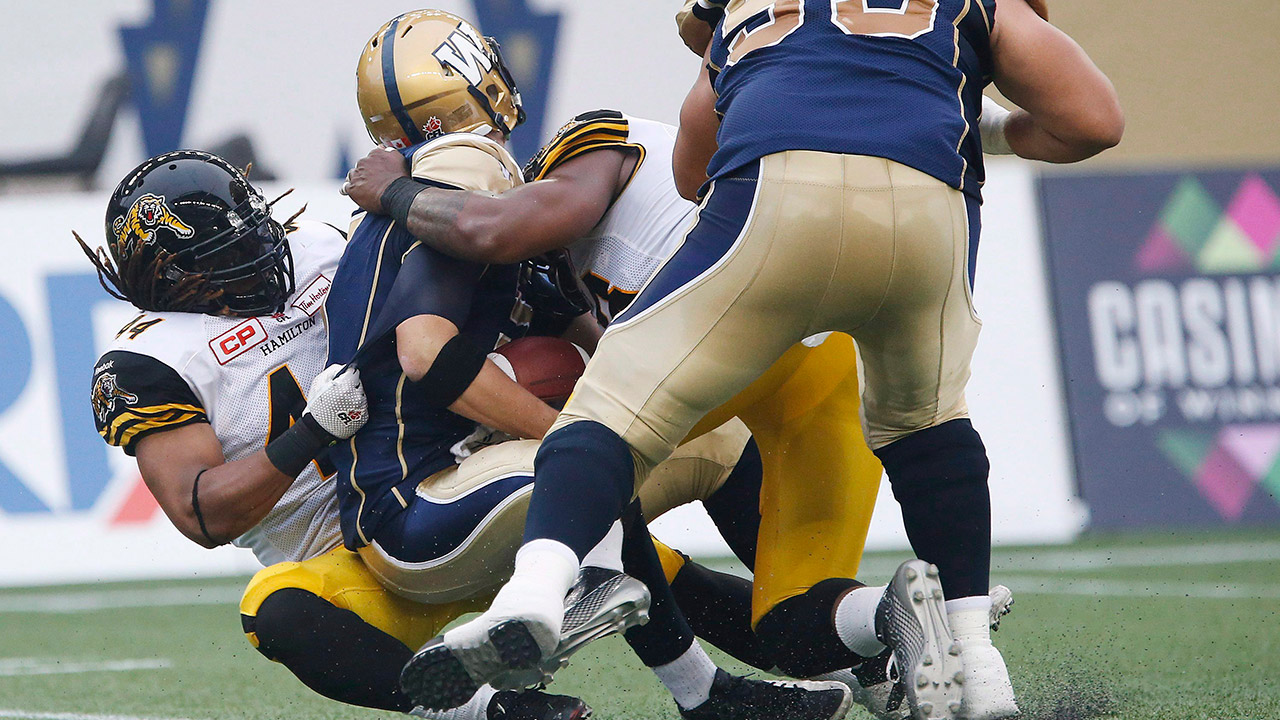 Hamilton Tiger-Cats' Taylor Reed (44) and Adrian Tracy (93) sack Winnipeg Blue Bombers' quarterback Drew Willy (5). (John Woods/CP)