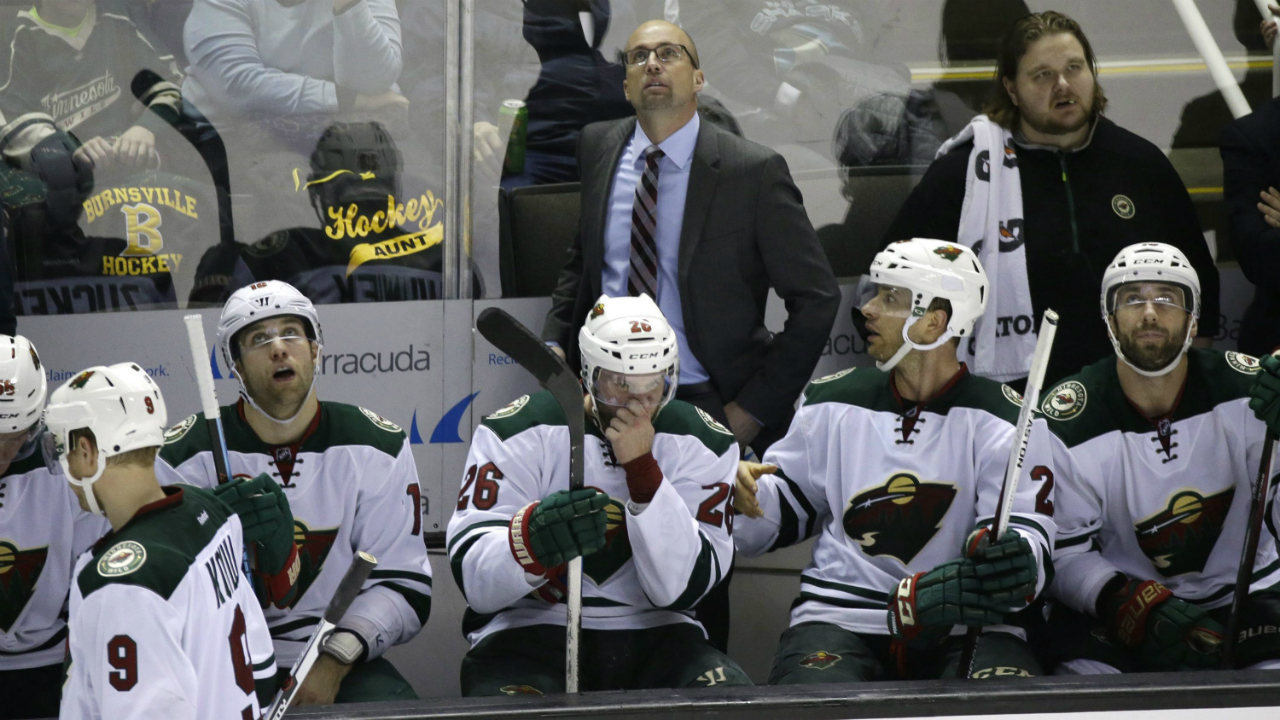 Minnesota-Wild-head-coach-Mike-Yeo-stands-behind-his-players-on-the-bench-and-watches-a-replay-of-the-San-Jose-Sharks-scoring-their-fourth-goal-in-the-third-period-of-an-NHL-hockey-game-Saturday,-Jan.-23,-2016,-in-San-Jose,-Calif.-San-Jose-won-the-game-4-3.-(AP-Photo/Eric-Risberg)