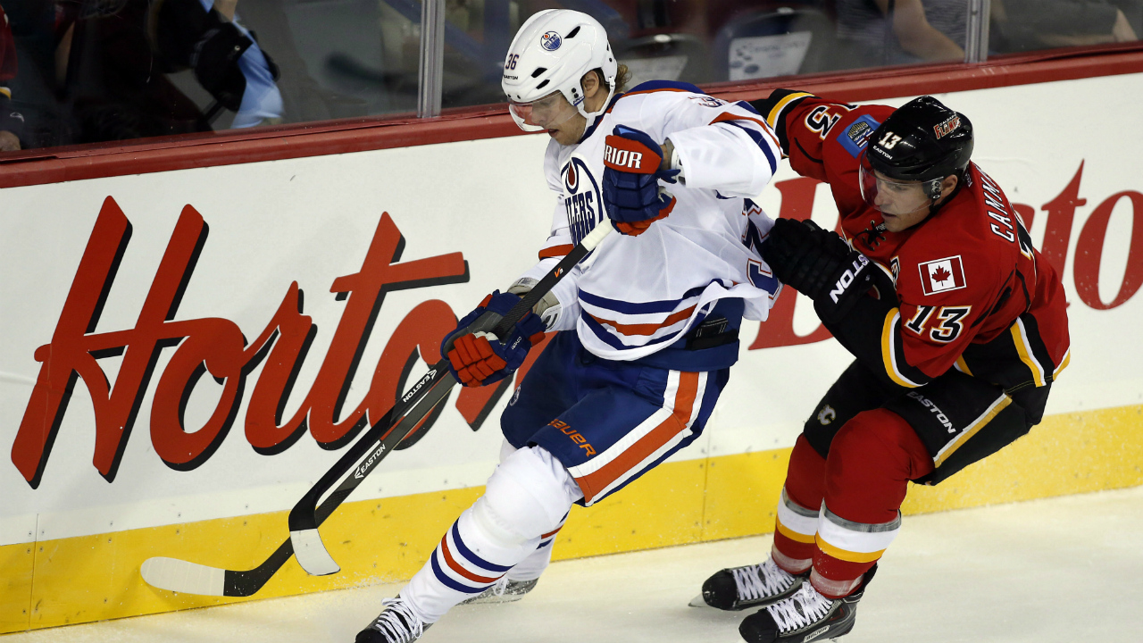 Edmonton-Oilers'-Philip-Larsen,-left,-from-Denmark,-grabs-the-puck-away-from-Calgary-Flames'-Mike-Cammalleri-during-first-period-NHL-pre-season-hockey-action-in-Calgary,-Alta.,-Saturday,-Sept.-14,-2013.THE-CANADIAN-PRESS/Jeff-McIntosh
