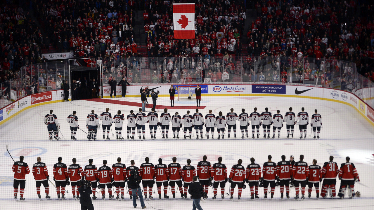 Team-Canada,-front,-and-Team-USA-watch-the-raising-of-the-flag-after-Canada-defeated-the-United-States-5-3-in-preliminary-round-hockey-action-at-the-IIHF-World-Junior-Championship-on-Wednesday,-December-31,-2014-in-Montreal.-THE-CANADIAN-PRESS/Ryan-Remiorz