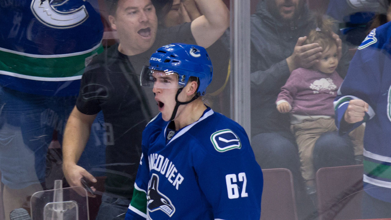 A man covers a child's ears as Vancouver Canucks' Joseph Labate celebrates his goal against the Edmonton Oilers. (Darryl Dyck/CP)