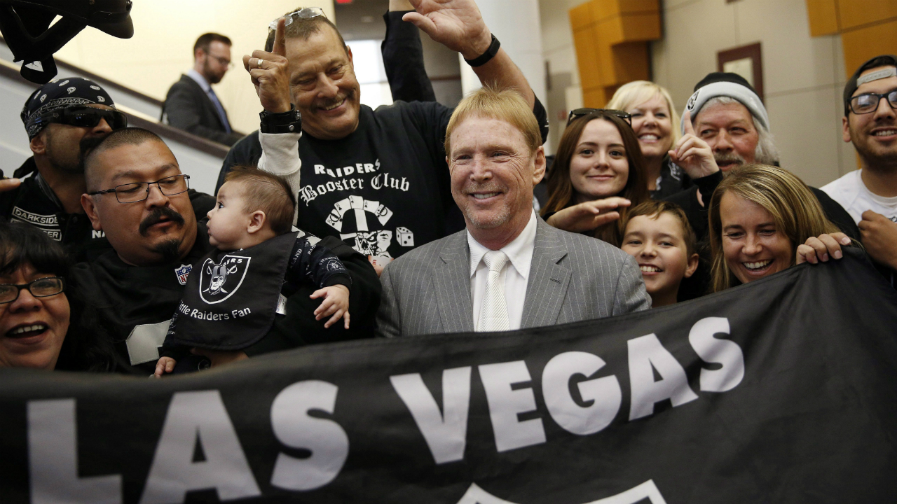 In-this-April-28,-2016,-file-photo,-Oakland-Raiders-owner-Mark-Davis,-center,-meets-with-Raiders-fans-after-speaking-at-a-meeting-of-the-Southern-Nevada-Tourism-Infrastructure-Committee-in-Las-Vegas.-America's-most-popular-sport-is-in-the-midst-of-its-greatest-migration-in-a-quarter-century.-In-a-little-over-a-year,-three-NFL-franchises-have-either-moved,-announced-a-resettlement-or-filed-paperwork-seeking-to-relocate.-(John-Locher/AP)