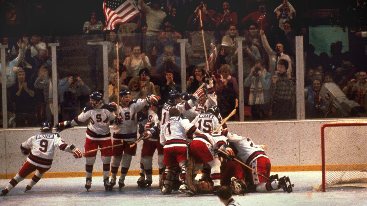 In this Feb. 22, 1980 file photo, the U.S. hockey team pounces on goalie Jim Craig after a 4-3 victory against the Soviets in the 1980 Olympics, as a flag waves from the partisan Lake Placid, N.Y. crowd. (AP Photo, File)