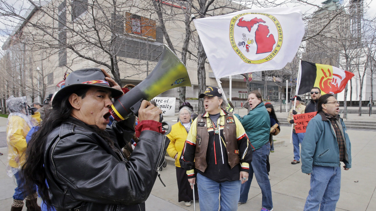 Philip-Yenyo,-executive-director-of-the-American-Indian-Movement-for-Ohio,-leads-a-protest-of-the-Cleveland-Indians-Chief-Wahoo-mascot-before-a-baseball-game-against-the-Detroit-Tigers-Friday,-April-10,-2015,-in-Cleveland.-(Mark-Duncan/AP)