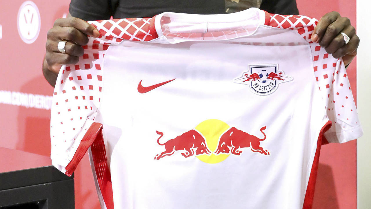 In-this-July-6,-2017-photo-new-team-member-Jean-Kevin-Augustin-shows-a-jersey-of-his-new-club-RB-Leipzig-during-a-press-conference-on-the-occasion-of-the-first-training-session-of-Bundesliga-soccer-club-RB-Leipzig-in-Leipzig,-Germany.-(Jan-Woitas/dpa-via-AP)