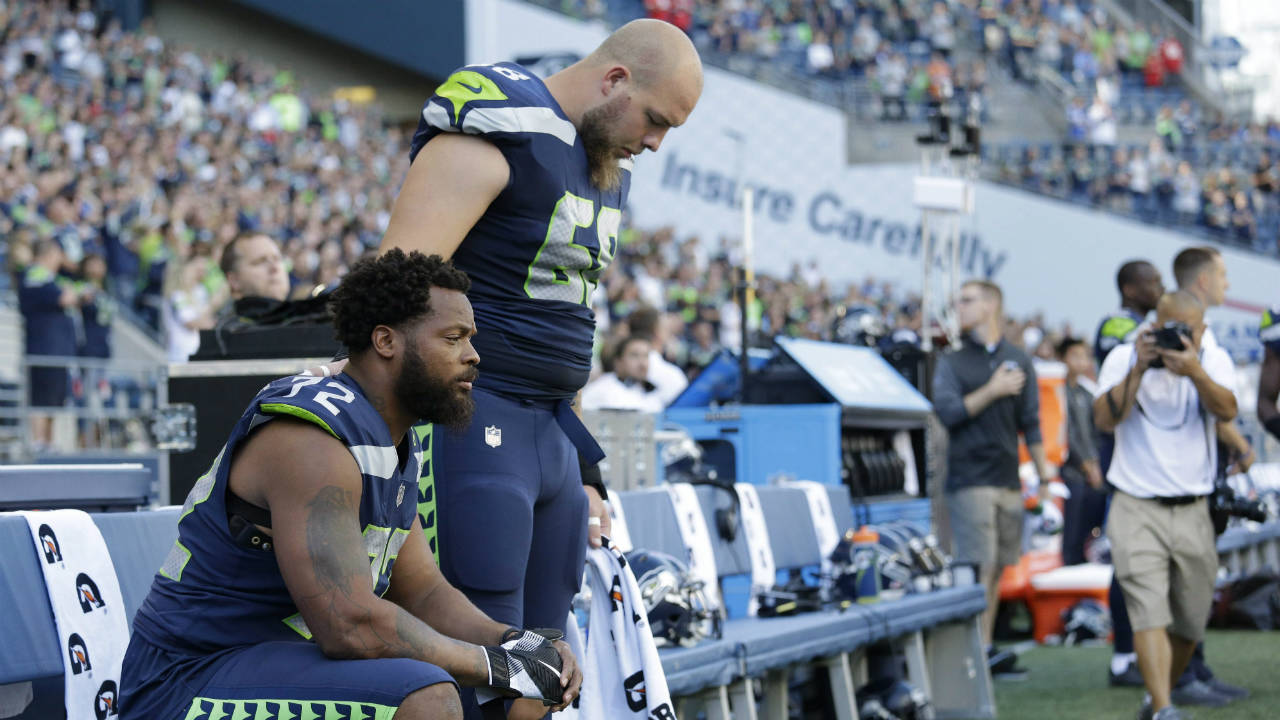 Seattle-Seahawks-defensive-end-Michael-Bennett,-left,-sits-during-the-singing-of-the-national-anthem-as-center-Justin-Britt,-right,-stands-next-to-him-before-an-NFL-football-preseason-game-against-the-Kansas-City-Chiefs,-Friday,-Aug.-25,-2017,-in-Seattle.-(Elaine-Thompson/AP)