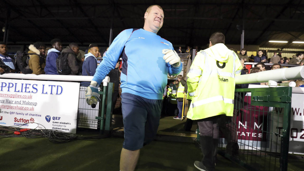 Sutton-reserve-goalkeeper-Wayne-Shaw-walks-near-the-playing-area-before-the-FA-Cup-5th-round-soccer-match-at-Gander-Green-Lane,-Sutton,-London,-Monday-Feb.-20,-2017.-A-backup-goalkeeper-paid-the-price-for-eating-a-meat-pie-during-his-team's-landmark-game-against-Arsenal,-resigning-from-Sutton-United-as-authorities-launched-investigations-into-the-apparent-betting-stunt.-A-British-newspaper's-betting-company,-which-sponsored-Sutton-United-for-Monday's-FA-Cup-game,-had-8-1-odds-that-overweight-reserve-goalkeeper-Wayne-Shaw-would-eat-a-meat-pie.-(Andrew-Matthews/PA-via-AP)