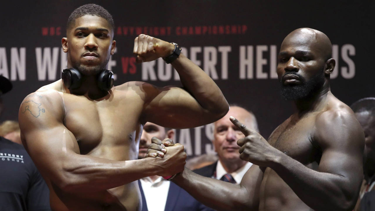 Britain's-Heavyweight-Champion-Anthony-Joshua,-left,-and-challenger-Carlos-Takam-pose-during-the-weigh-in-at-Motorpoint-Arena-in-Cardiff,-Wales,-Friday,-Oct.-27,-2017.-Joshua-will-take-on-Takam-in-a-world-title-fight-in-Cardiff-on-Saturday.-(Nick-Potts/PA-via-AP)