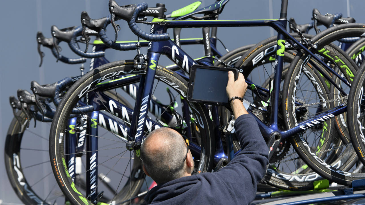 A-staff-member-of-the-International-Cycling-Union-(UCI)-holds-a-tablet-to-scan-a-bicycle-of-team-Movistar.-(Jean-Christophe-Bott/Keystone-via-AP)