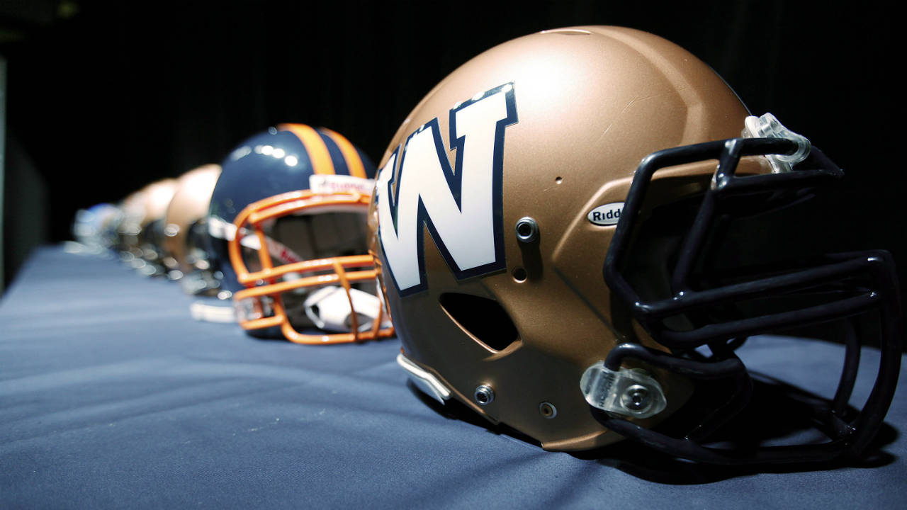 The-new-Winnipeg-Blue-Bombers-1980s-style-logo-is-unveiled-at-a-press-conference-at-Canada-Inn-Stadium-in-Winnipeg,-Tuesday,-April-24,-2012.-The-CFL-club-is-changing-its-helmet-logo-back-to-a-simple-'W'.-(John-Woods/CP)