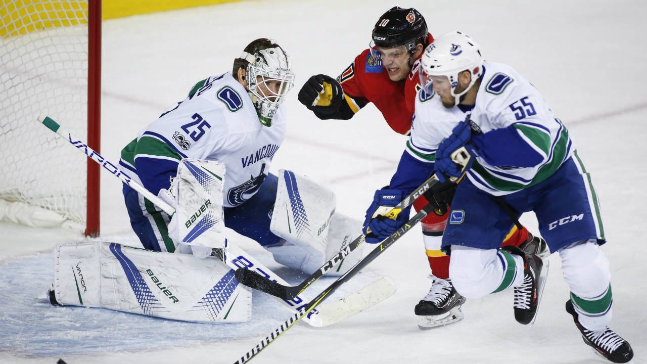 Vancouver-Canucks-goalie-Jacob-Markstrom,-left,-from-Sweden,-looks-on-as-Calgary-Flames'-Kris-Versteeg,-chases-a-lose-puck-with-Canucks'-Alex-Biega-during-first-period-NHL-hockey-action-in-Calgary,-Tuesday,-Nov.-7,-2017.-(Jeff-McIntosh/CP)