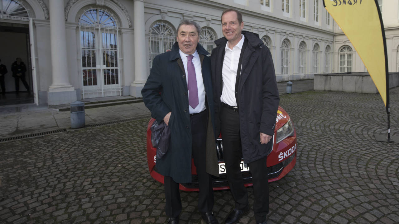 Tour-de-France-director-Christian-Prudhomme,-background-and-former-cyclist-Eddy-Merckx-pose-with-the-official-car-prior-to-a-presentation-of-the-2019-Tour-de-France-cycling-race-in-Brussels-on-Tuesday,-Jan.-16,-2018.-The-start-of-the-2019-Tour-de-France-will-be-all-about-honoring-Merckx-in-his-hometown-Brussels.-Merckx-_-known-as-The-Cannibal-for-his-ferocious-taste-for-victory-_-won-his-first-of-five-Tours-in-1969-and-half-a-century-later-still-sees-it-as-one-of-the-major-accomplishments-of-a-cyclists-generally-seen-as-the-greatest-ever.-(Olivier-Matthys/AP)