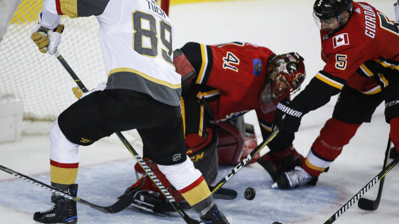 Vegas-Golden-Knights'-Alex-Tuch,-left,-tries-for-a-rebound-as-Calgary-Flames-goalie-Mike-Smith-scrambles-to-grab-the-puck-during-second-period-NHL-hockey-action-in-Calgary,-Tuesday,-Jan.-30,-2018.-(Jeff-McIntosh/CP)