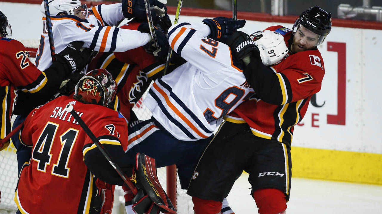 Edmonton-Oilers-centre-Connor-McDavid-(97)-is-hauled-down-by-Calgary-Flames-defenseman-TJ-Brodie-(7)-as-goaltender-Mike-Smith-(41)-looks-on-during-third-period-NHL-hockey-action-in-Calgary,-Tuesday,-March-13,-2018.-(Jeff-McIntosh/CP)