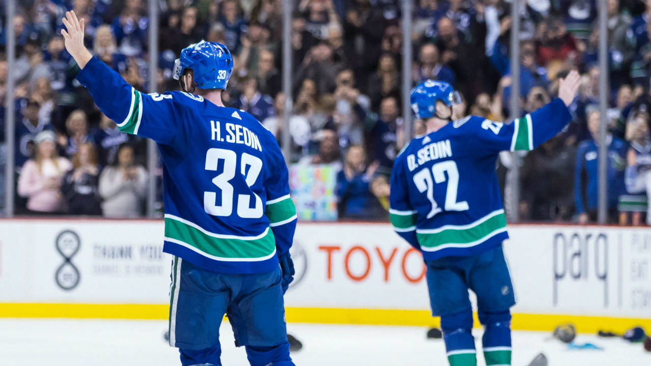 Vancouver Canucks' Henrik Sedin, left, and his twin brother Daniel Sedin, both of Sweden, wave to the crowd after defeating the Arizona Coyotes 4-3 in their last home NHL hockey game, in Vancouver on Thursday, April 5, 2018. The brothers announced this week they would be retiring from the NHL at the end of this season. (Darryl Dyck/CP)