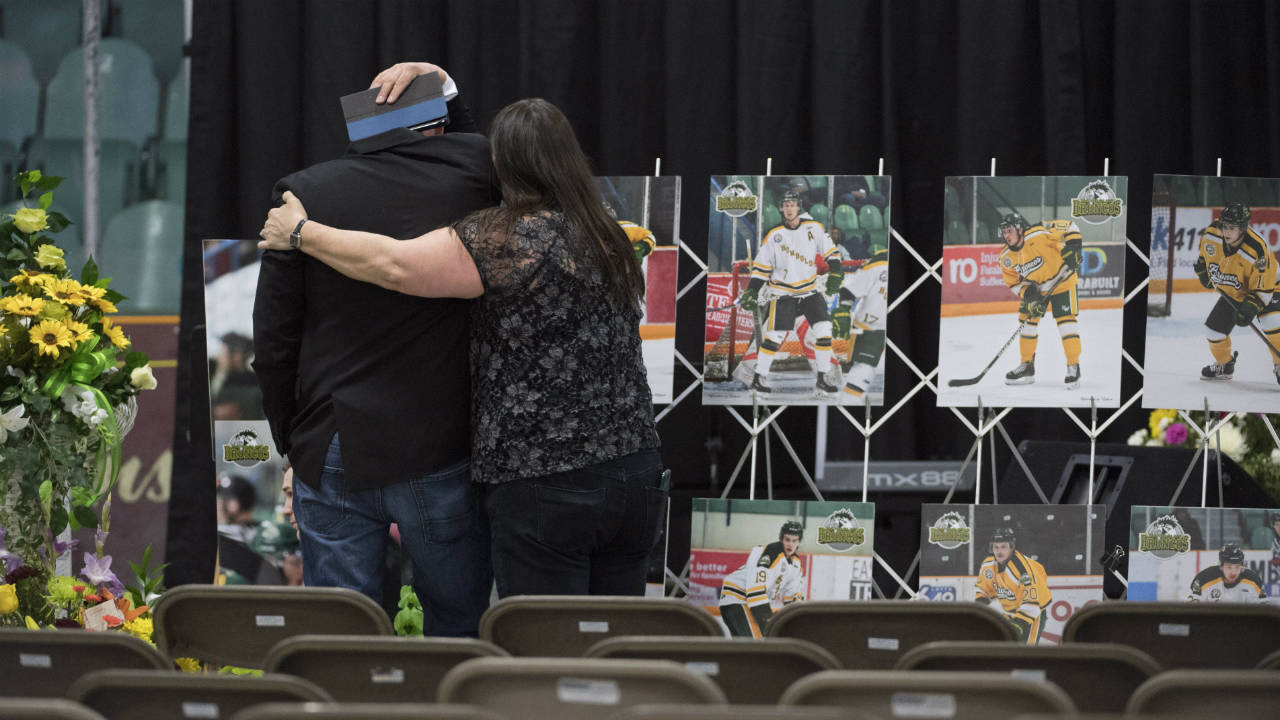 A-man-is-comforted-as-he-looks-at-photographs-prior-to-a-vigil-at-the-Elgar-Petersen-Arena,-home-of-the-Humboldt-Broncos,-to-honour-the-victims-of-a-fatal-bus-accident-in-Humboldt,-Sask.-on-Sunday,-April-8,-2018.-(Jonathan-Hayward/CP)