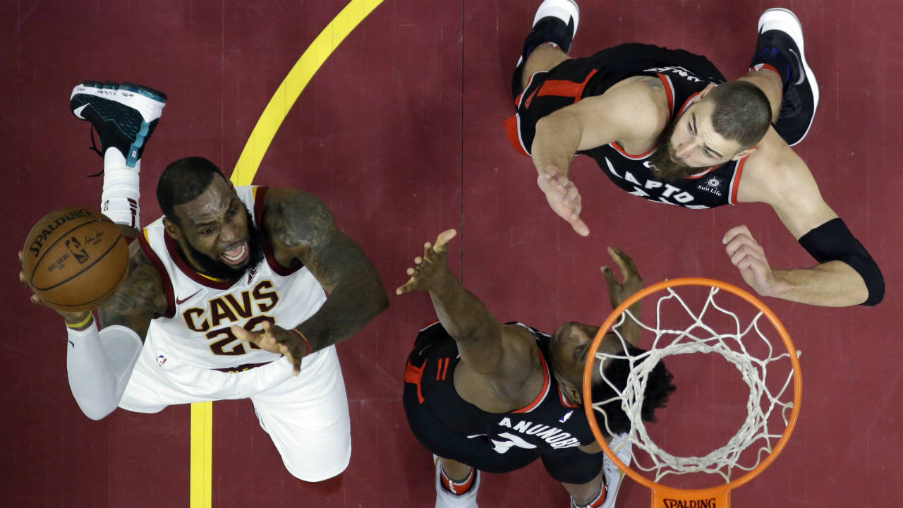 Cleveland-Cavaliers'-LeBron-James-shoots-as-Toronto-Raptors'-OG-Anunoby-and-Jonas-Valanciunas,-right,-defend-during-the-first-half-of-an-NBA-basketball-game-Tuesday,-April-3,-2018,-in-Cleveland.-(Tony-Dejak/AP)