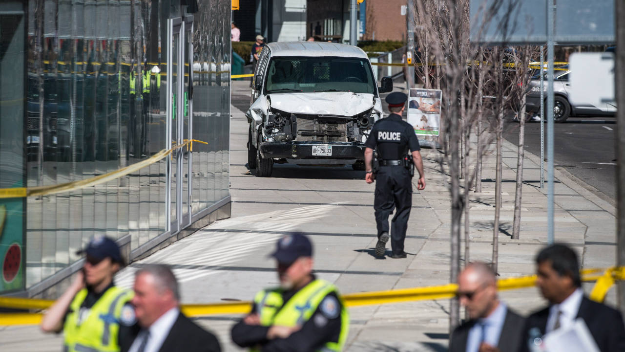 Police-are-seen-near-a-damaged-van-in-Toronto-after-a-van-mounted-a-sidewalk-crashing-into-a-number-of-pedestrians-on-Monday,-April-23,-2018.-(Aaron-Vincent-Elkaim/CP)