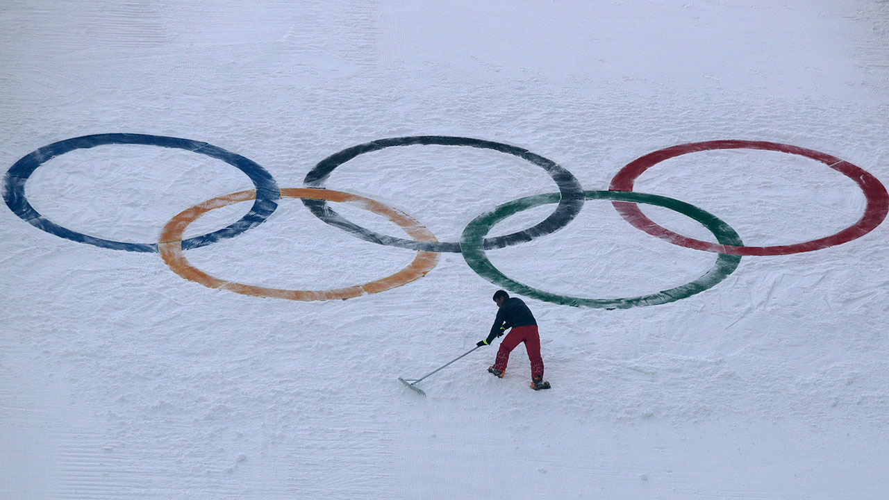 A worker grooms the snow after installing a set of Olympic Rings. (Charlie Riedel/AP)