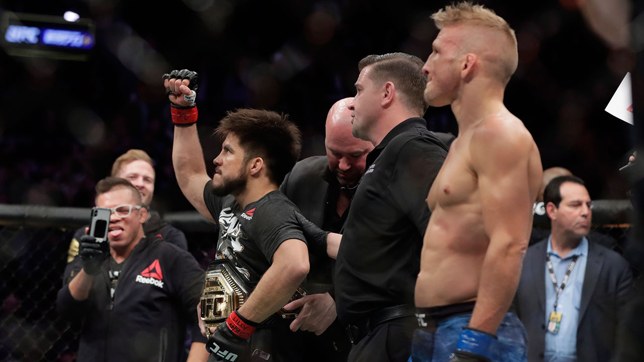 tj-dillashaw-looks-on-as-henry-cejudo-has-ufc-belt-wrapped-around-waist