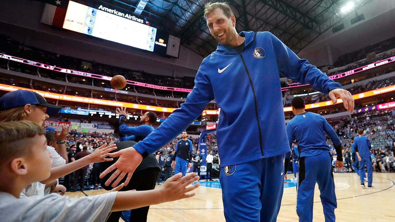 Dallas Mavericks forward Dirk Nowitzki reaches out to young fans on the sideline while warming up. (LM Otero/AP)