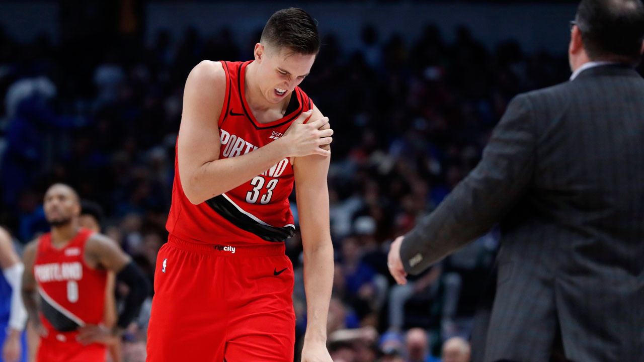 Portland Trail Blazers forward Zach Collins (33) holds his left shoulder as he walks to the bench for assistance after suffering an unknown injury in the second half of an NBA basketball game against the Dallas Mavericks. (AP Photo/Tony Gutierrez)