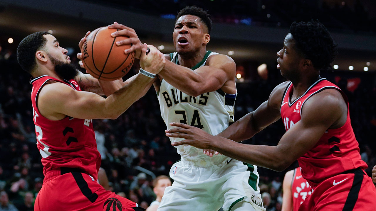 Milwaukee Bucks' Giannis Antetokounmpo is fouled as he drives between Toronto Raptors' Fred VanVleet and OG Anunoby. (Morry Gash/AP)