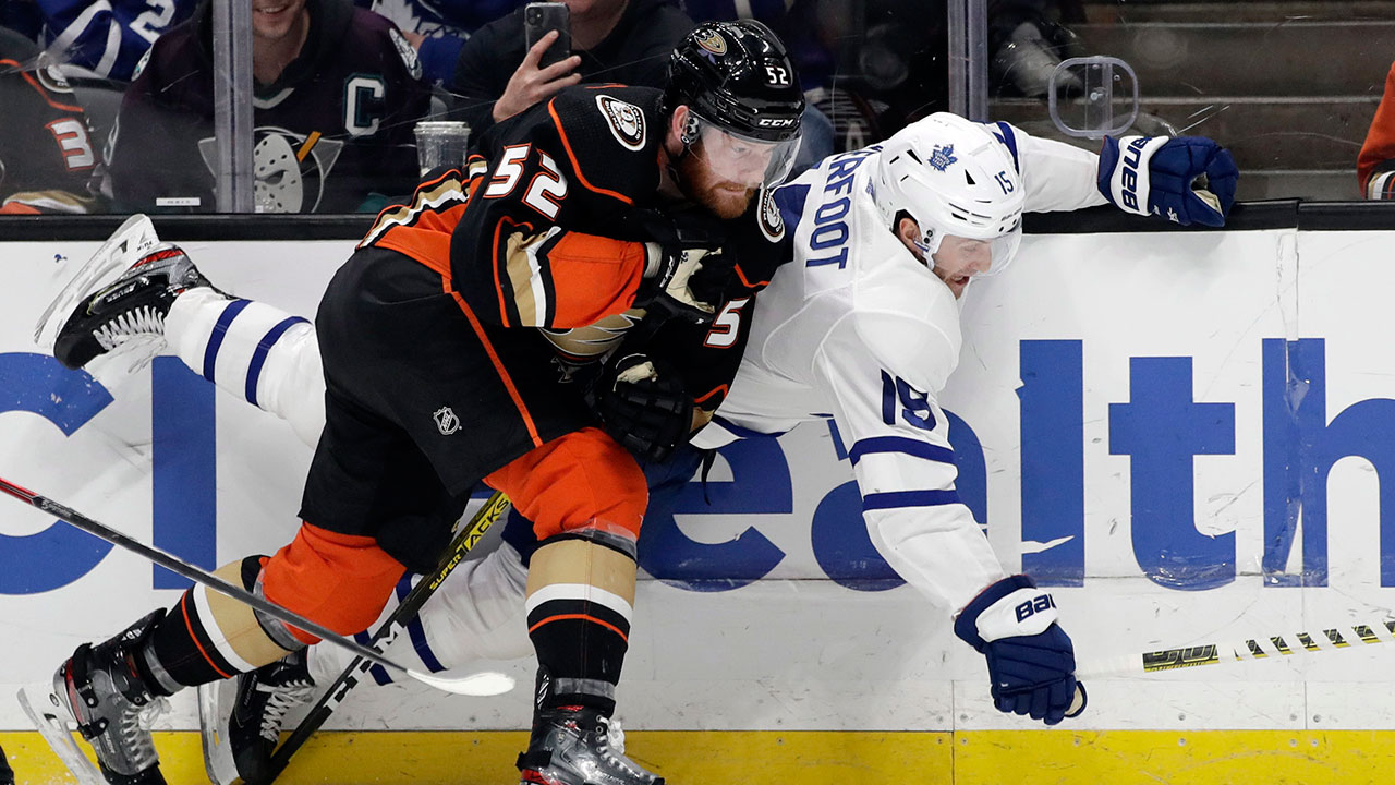 Anaheim Ducks' Matt Irwin, left, pushes Toronto Maple Leafs' Alexander Kerfoot against the boards during the first period of an NHL hockey game Friday, March 6, 2020, in Anaheim, Calif. (AP Photo/Marcio Jose Sanchez)