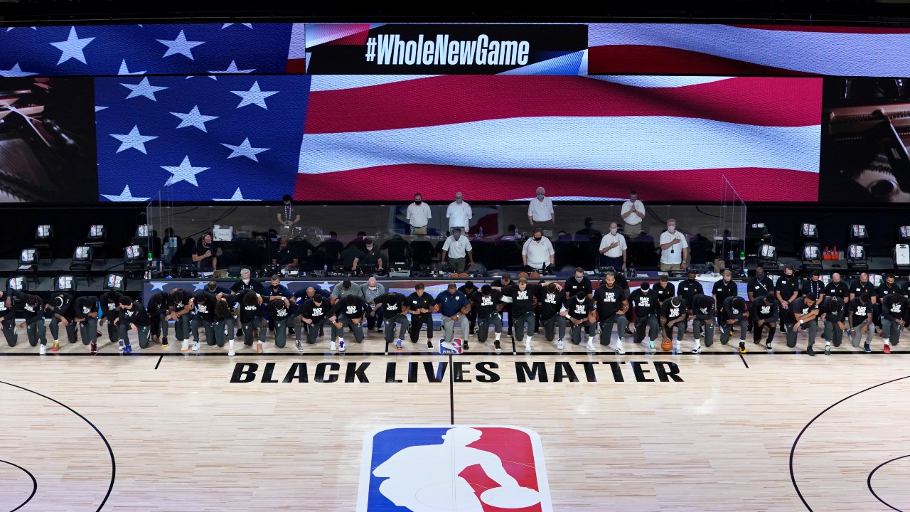 Members of the New Orleans Pelicans and Utah Jazz kneel together around the Black Lives Matter logo on the court during the national anthem. (Ashley Landis/AP)