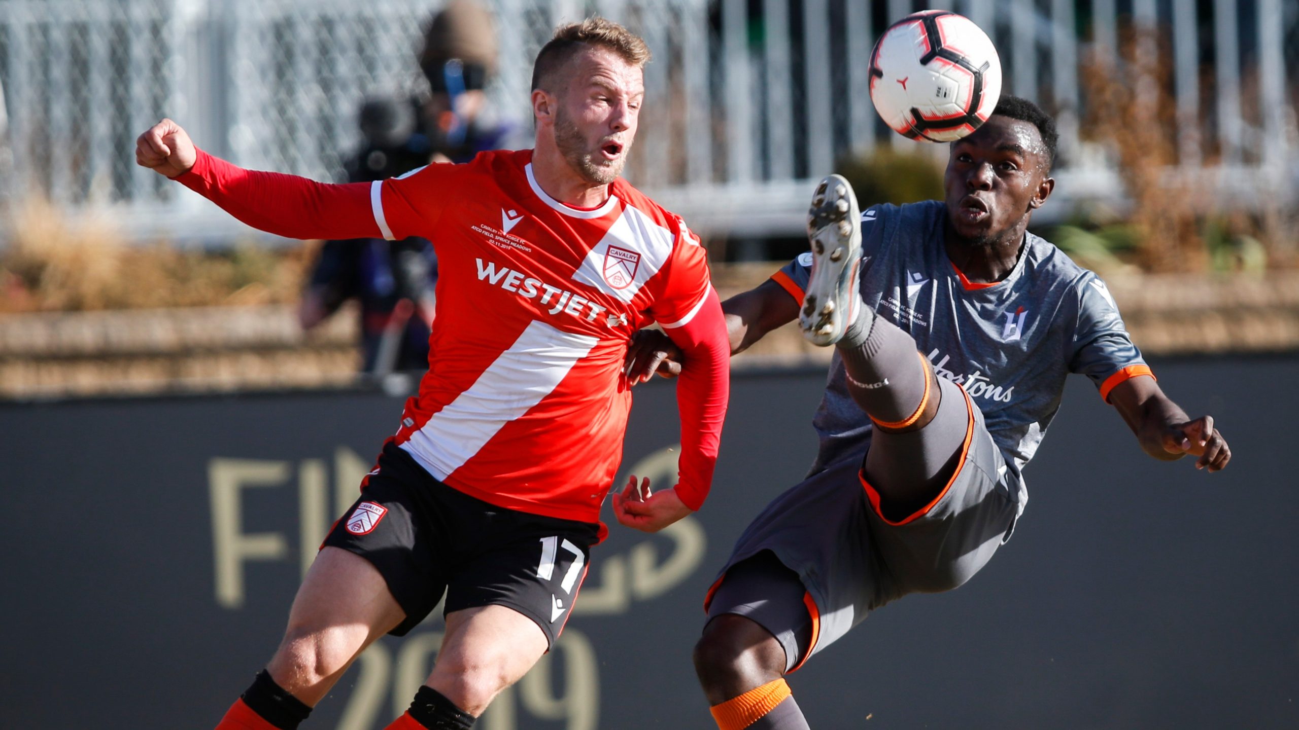 Hamilton Forge's Kwame Awuah, right, kicks the ball as Calgary Cavalry's Nico Pasquotti looks on during Canadian Premier League soccer finals action. (Jeff McIntosh/CP)