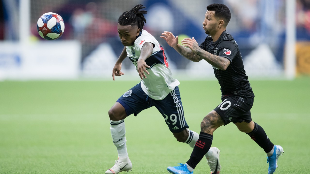 Vancouver Whitecaps' Yordy Reyna, left, and D.C. United's Luciano Acosta vie for the ball during the second half of an MLS soccer game. (Darryl Dyck/CP)