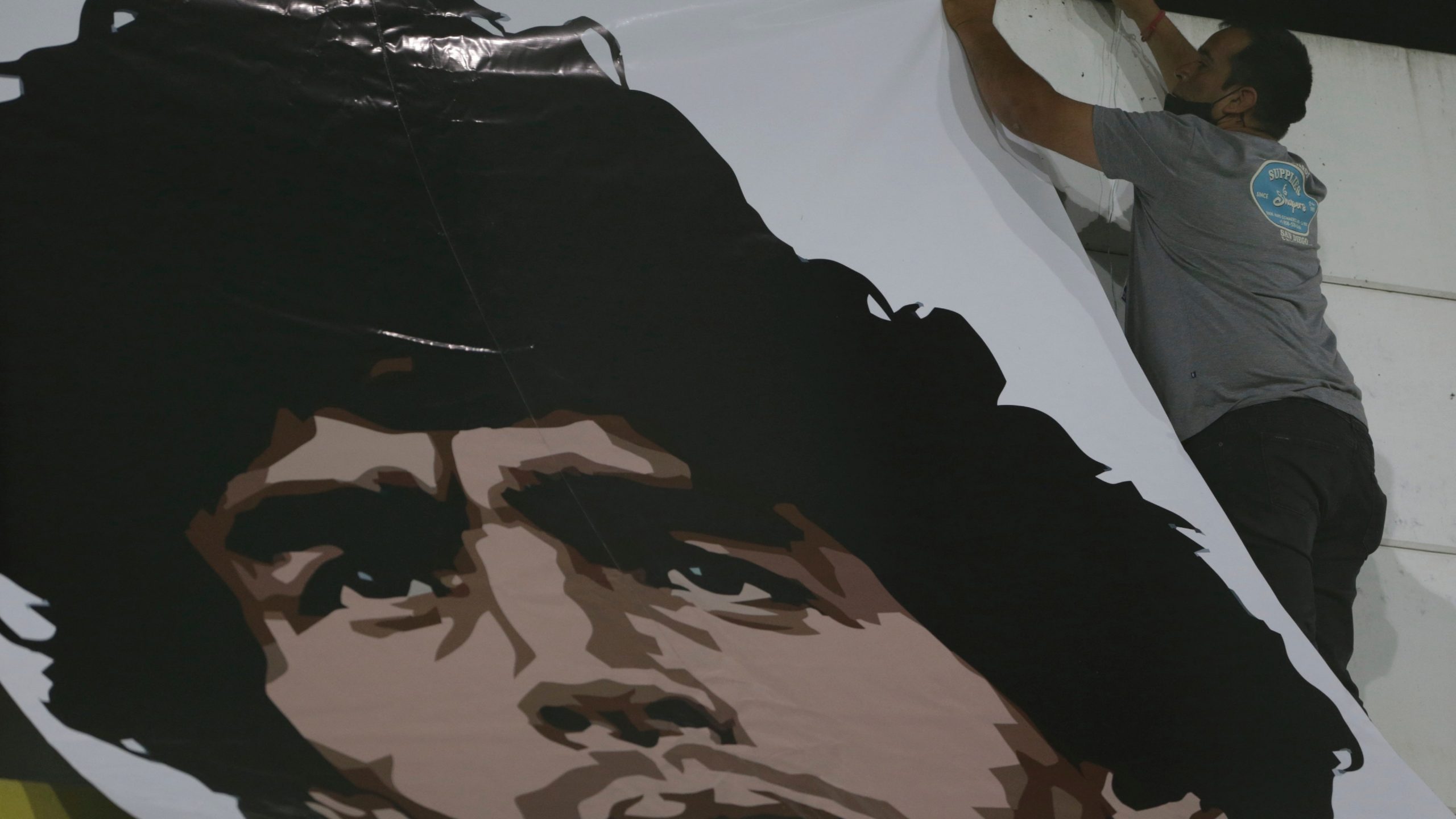 A worker installs a banner with the image of Diego Maradona at the Norberto Tomaghello stadium before a Copa Sudamericana Soccer match between Argentina's Defensa y Justicia and Brazil's Vasco Da Gama. (Daniel Jayo/Pool via AP)