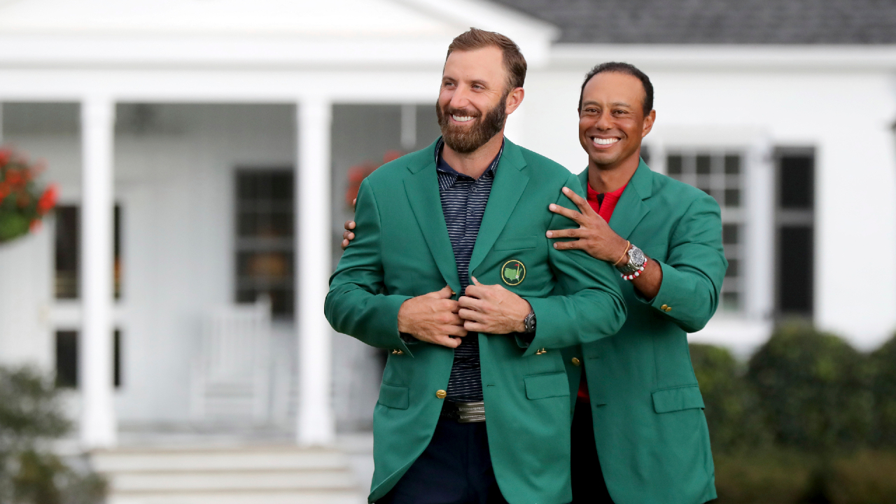 Last year's Masters champion Tiger Woods, right, presents Dustin Johnson with his first green jacket after winning the Masters golf tournament Sunday, Nov. 15, 2020, in Augusta, Ga. (Curtis Compton/Atlanta Journal-Constitution/AP
