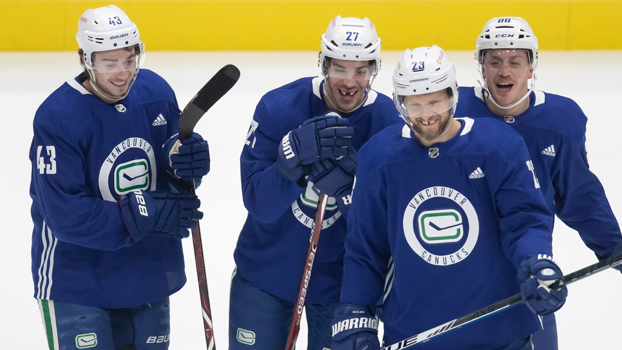 Vancouver Canucks defencemen Quinn Hughes, from left to right, Travis Hamonic, Nate Schmidt and Alexander Edler, of Sweden, laugh during the NHL hockey team's training camp in Vancouver, on Monday, January 11, 2021. (Darryl Dyck/CP)