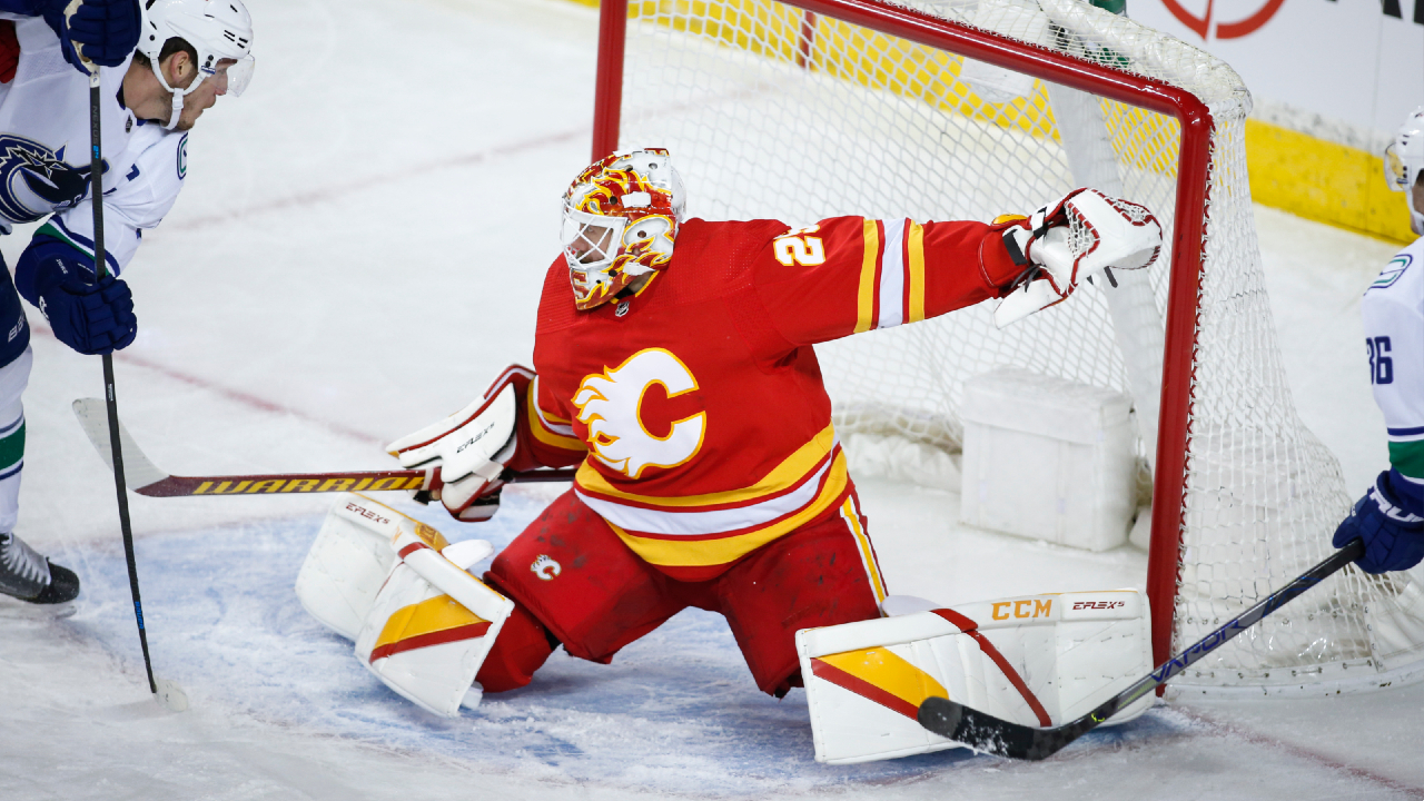 Vancouver Canucks captain Bo Horvat, left, looks on as the puck passes over Calgary Flames goalie Jacob Markstrom. (Jeff McIntosh/CP)