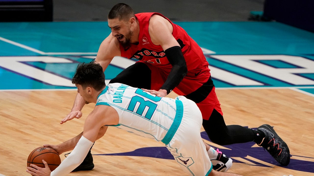 Toronto Raptors center Alex Len, top, and Charlotte Hornets guard Nate Darling dive for the ball during the second half of an NBA preseason basketball game. (Chris Carlson/AP)