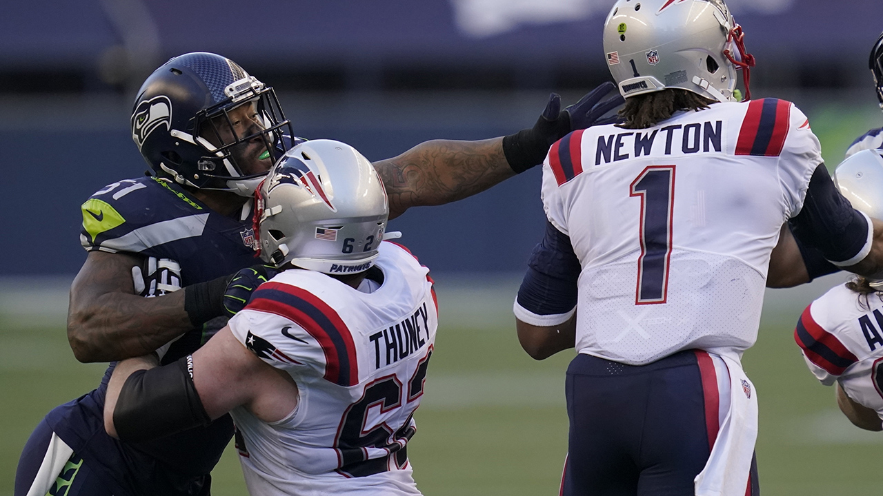 Seattle Seahawks linebacker Bruce Irvin, letft, is blocked by New England Patriots offensive guard Joe Thuney as he pressures quarterback Cam Newton (1) during the first half of an NFL football game, in Seattle. (Elaine Thompson/AP)