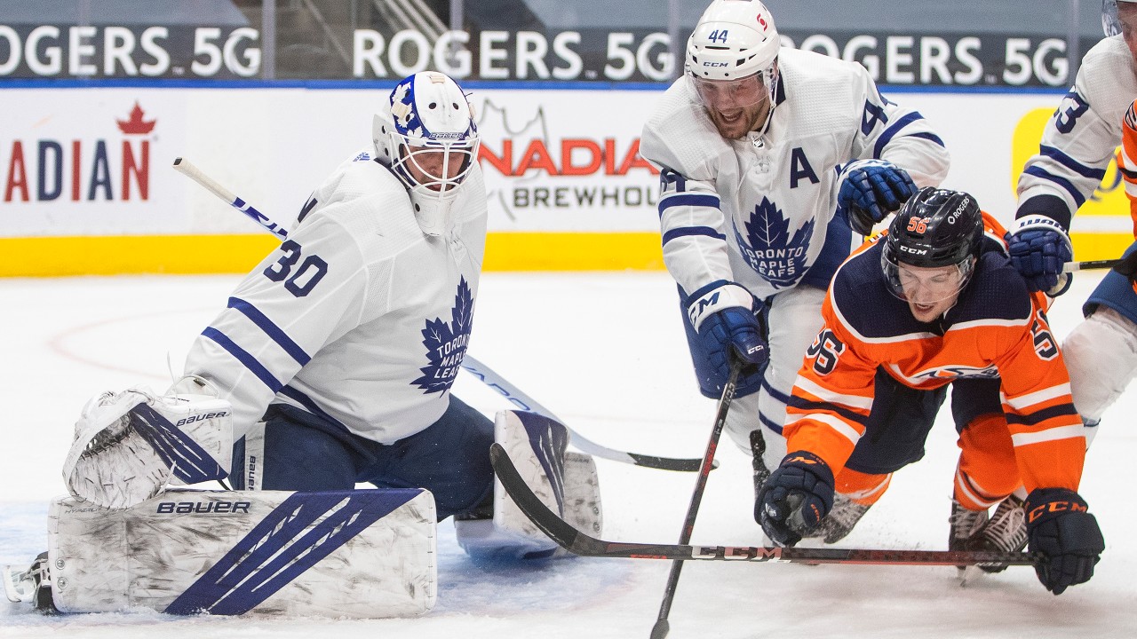 Edmonton Oilers' Kailer Yamamoto (56) and Toronto Maple Leafs' Morgan Rielly (44) reach for the rebound from Leafs goalie Michael Hutchinson (30) during second period NHL action in Edmonton on Monday, March 1, 2021. (Jason Franson / CP)