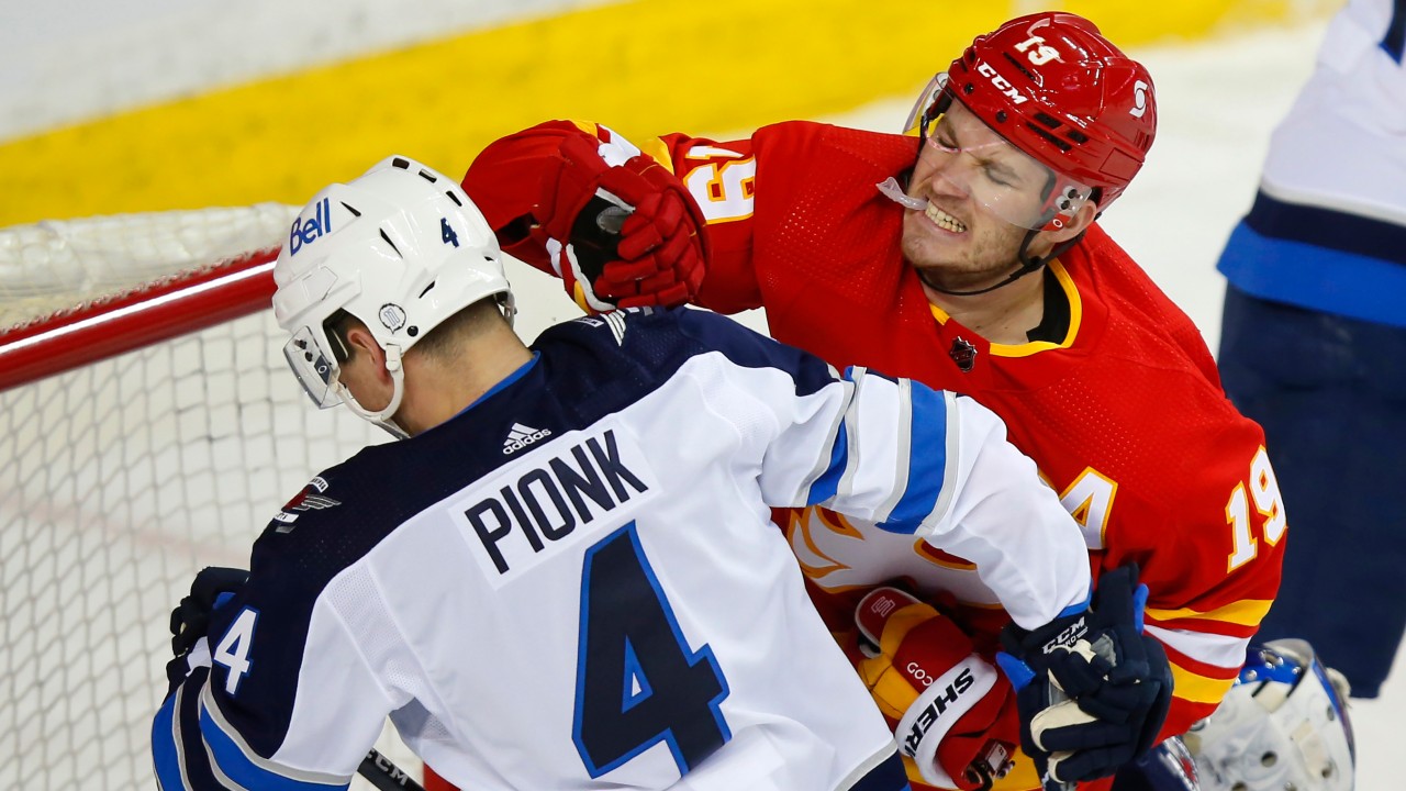 Winnipeg Jets' Neal Pionk and Calgary Flames' Matthew Tkachuk exchange blows in front of the Jet's net during first period NHL hockey action in Calgary, Alta., Saturday, March 27, 2021. (Todd Korol / CP)