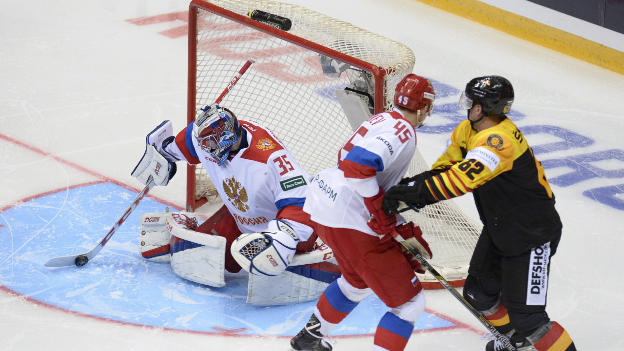 Russia's goalie Alexander Sudnitsin, left, controls the puck as his teammate Vladislav Provolnev, centre, blocks Germany's Simon Danner. (Artur Lebedev/AP)