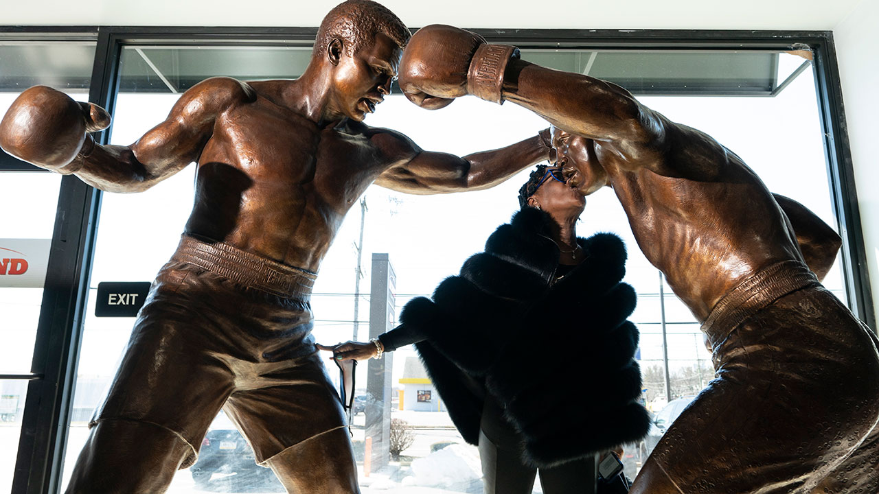Weatta Frazier Collins kisses a statue of her father Joe Frazier, right, fighting Muhammad Ali, on the 50th anniversary of the boxers' World Heavyweight championship boxing bout, at the Joe Hand Gym in Feasterville, Pa., Monday, March 8, 2021. (Matt Rourke/AP)