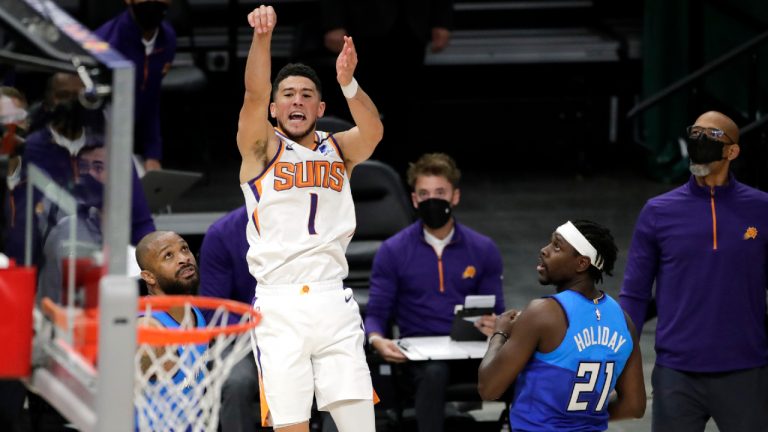 Phoenix Suns' Devin Booker, right, is fouled by Milwaukee Bucks' P.J. Tucker, left, during overtime of an NBA basketball game Monday, April 19, 2021, in Milwaukee. (AP Photo/Aaron Gash)