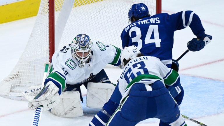 Vancouver Canucks goaltender Braden Holtby (49) pokes the puck away from Toronto Maple Leafs forward Auston Matthews (34) as Canucks defenceman Jalen Chatfield (63) keeps close during first period NHL hockey action in Toronto on Thursday, April 29, 2021. (THE CANADIAN PRESS/Nathan Denette)