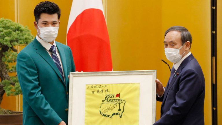 Hideki Matsuyama, left, hands a gift to Prime Minister Yoshihide Suga, right, at the prime minister's office in Tokyo. (Masanori Takei/Kyodo News via AP)