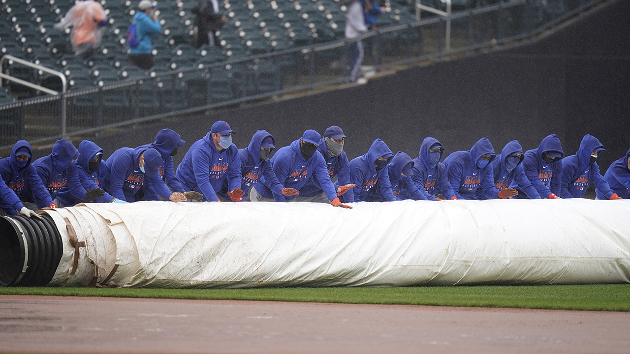New York Mets employees roll a tarp over the field during a delay in the first inning of a baseball game against the Miami Marlins at Citi Field, Sunday, April 11, 2021, in New York. (Seth Wenig/AP)