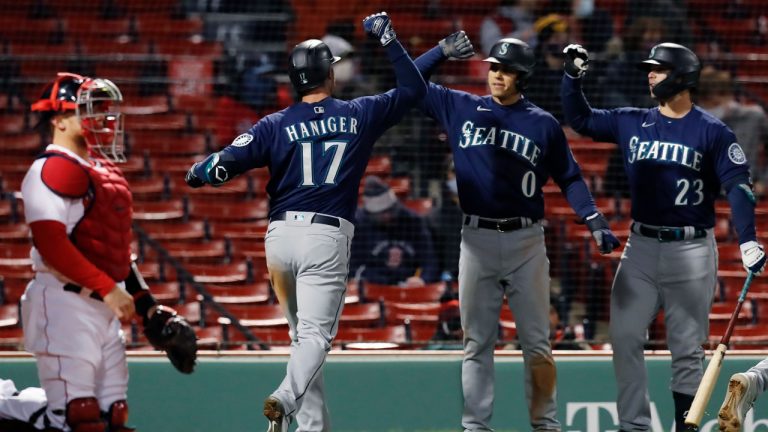 Boston Red Sox catcher Christian Vazquez, left, kneels at home plate as Seattle Mariners' Mitch Haniger (17) celebrates his three-run home run that also drove in Sam Haggerty (0) during the 10th inning. (Michael Dwyer/AP)