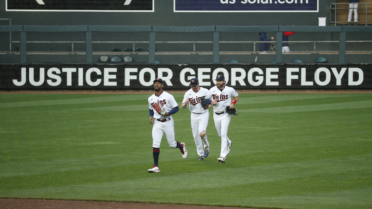 Minnesota Twins' Byron Buxton, Kyle Garlick, and Jake Cave, left to right, celebrate the 10-2 win over Seattle Mariners in front of a Target Field sign that reads "Justice for George Floyd" at a baseball game Thursday, April 8, 2021, in Minneapolis. (AP Photo/Bruce Kluckhohn)
