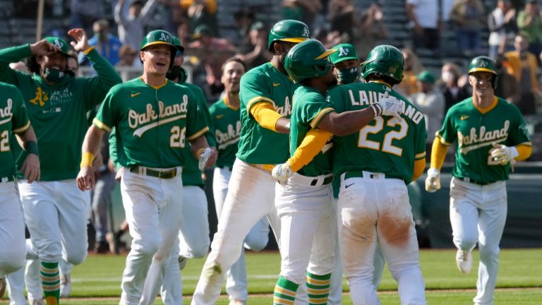 Oakland Athletics' Ramon Laureano (22) celebrates with teammates after two runs scored on a throwing error by Minnesota Twins third baseman Luis Arraez during the 10th inning of a baseball game Wednesday, April 21, 2021, in Oakland, Calif. Laureano safe at first. Oakland won 13-12. (AP Photo/Tony Avelar)